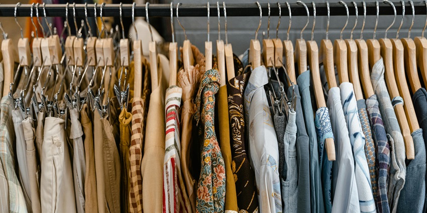 Assorted clothes hanging on a black steel rack in a boutique setting.