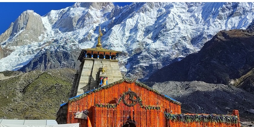 A picture of the main shrine of the Kedarnath Temple with views of the Himalayas in the background