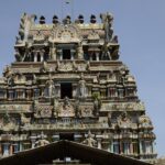 Kolanjiappar Temple featuring entrance and a woman worshipping and small shops nearby