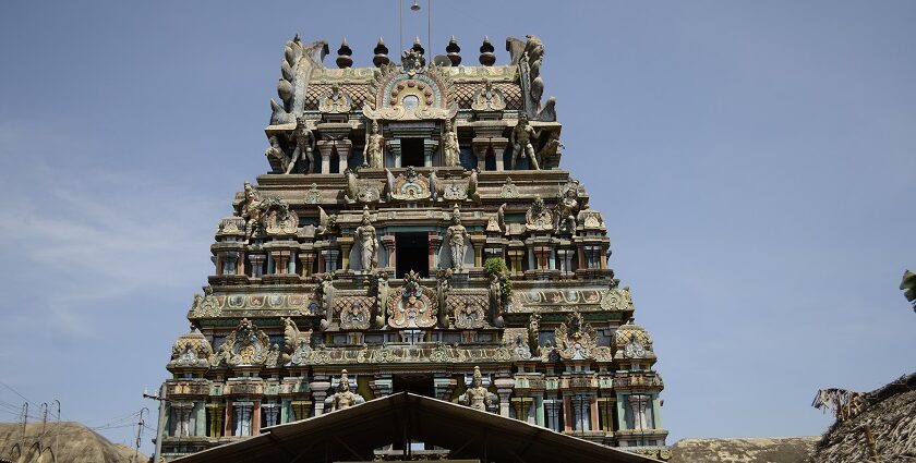 Kolanjiappar Temple featuring entrance and a woman worshipping and small shops nearby