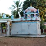 Konerirajapuram Temple with detailed Chola stone carvings behind a wall and trees