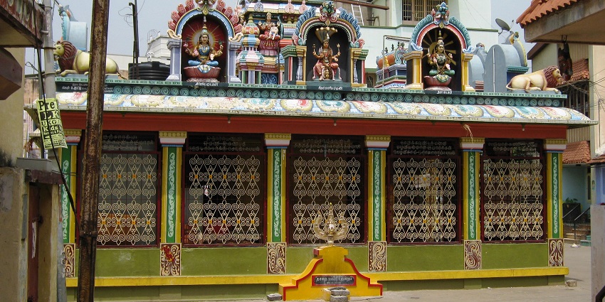 An outer view of a beautiful temple that has intricate carving and is vibrantly coloured