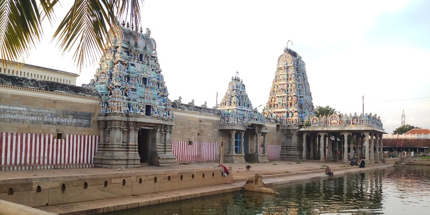 Koviloor Temple showcasing colourful gopurams with a sacred water reservoir in front of it