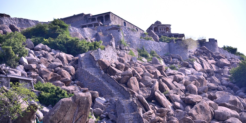 Krishnagiri Fort stands atop a hill against a blue sky, a place to visit in Krishnagiri.
