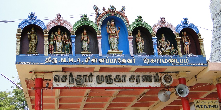 Murugan Temple with its tall tower and intricate designs against a clear sky.