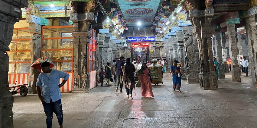 Inside view of Adi Kumbeswarar Temple with people walking across the long corridor