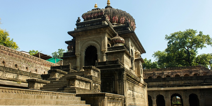 An image of a close-up of a brown metal bell hanging, reminiscent of Kunjapuri Temple.