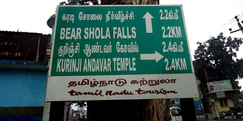 Signboard on a tree showing the distance to Kurinji Andavar Temple in Kodaikanal