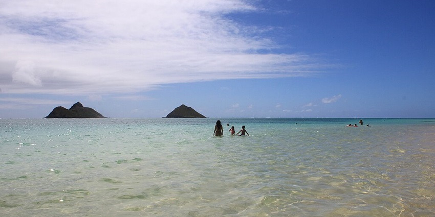 Lanikai Beach with people enjoying the sea and multiple distant mountains visible
