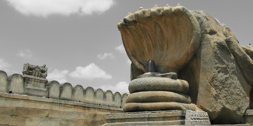 A five-headed snake is carved out from a stone and showcased protecting a Shiva Linga.