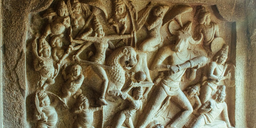 A close-up view of an ancient Indian temple’s sculpture with detailed carving depicting figures.