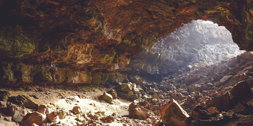 Rock formations with layered textures surrounded by more rocks inside the Gupta Dham caves