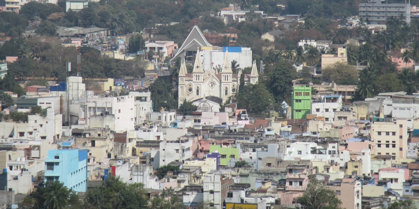 View the city from a hilltop, showcasing buildings, landscape and the surrounding greenery.