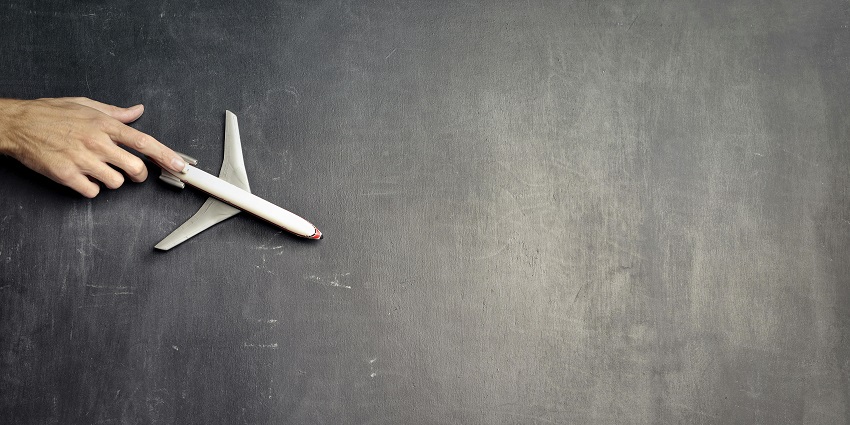 A breathtaking view of a white toy aeroplane on a black surface during the daytime.