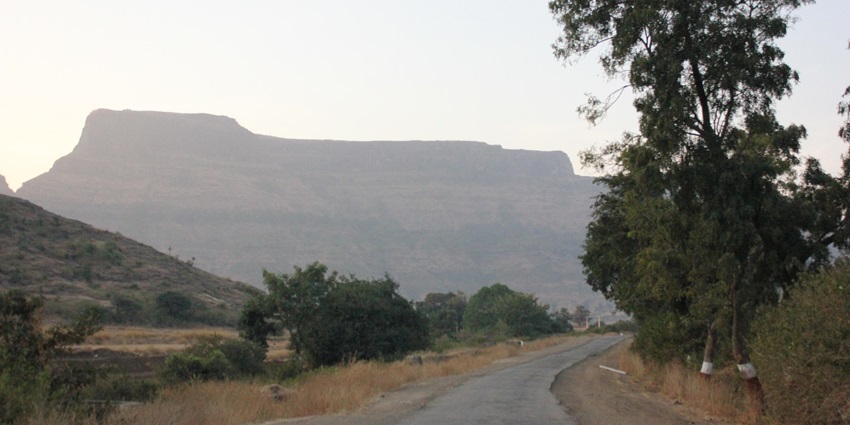 Distant picture of Mulher Fort, surrounded by lush hills in Nashik district, Maharashtra.