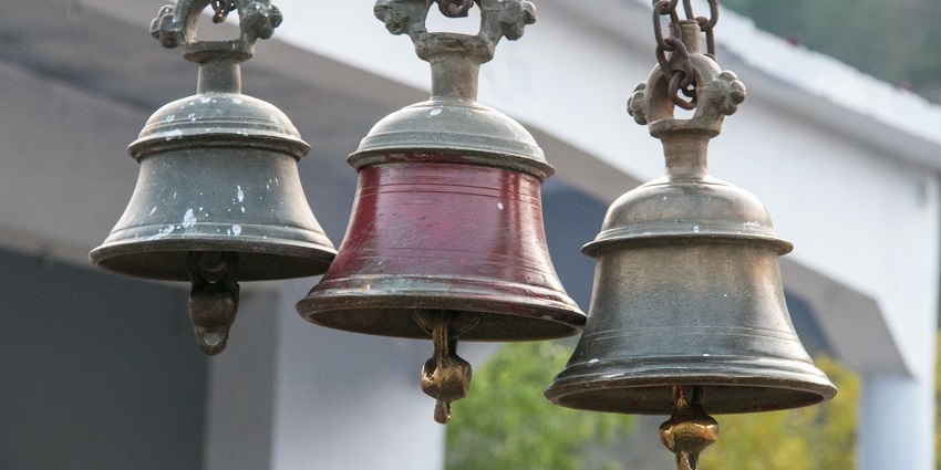 A placid view of temple bells and columns showcasing intricate carvings and traditional design