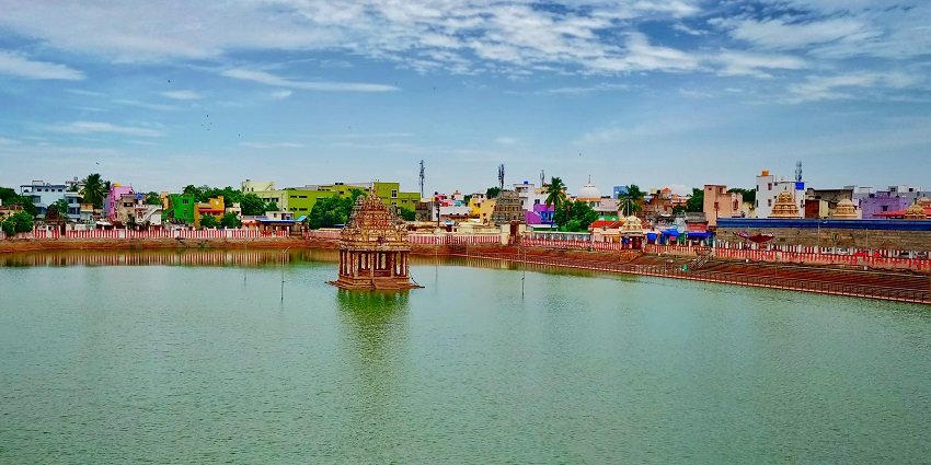 Area of Tiruvallur with a temple visible at a distance surrounded by other buildings.