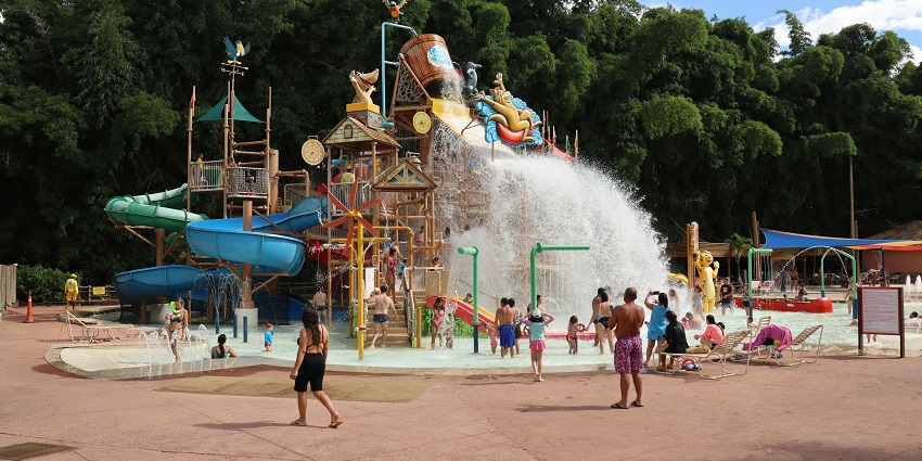 Excited people enjoying a water park with colorful slides, splashing water