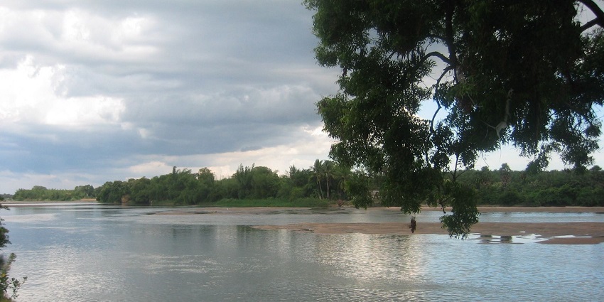 Calm waters of the Kaveri River flowing through Thiruvaiyaru temple, bordered by lush greenery.