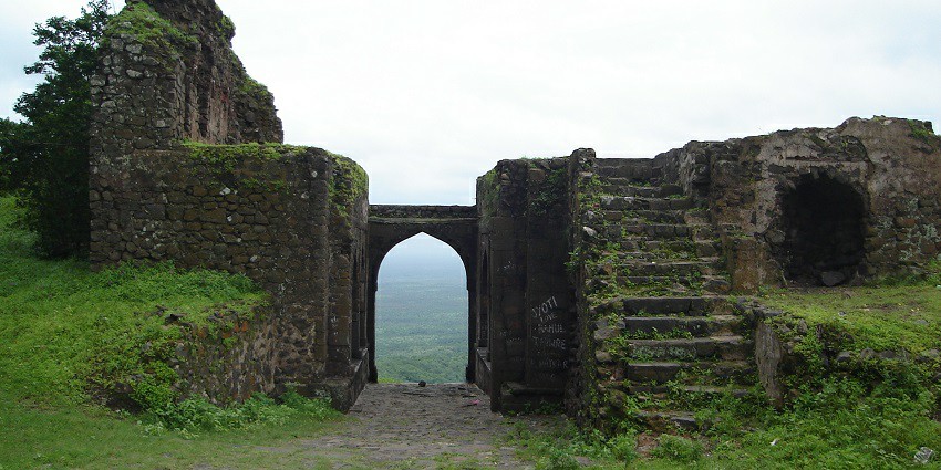 Historic Asurgarh Fort with rugged stone walls, surrounded by scenic landscapes under a bright sky