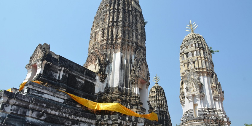 Several ancient, tiered stupas with carvings stand against a clear, bright blue sky.