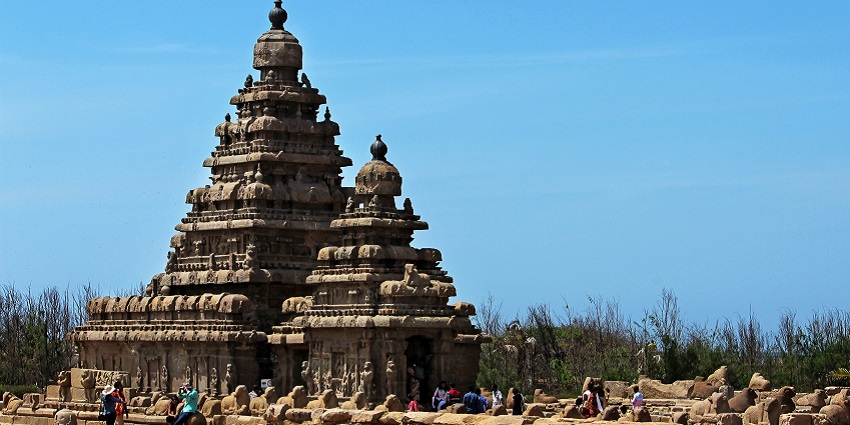 A distant side view of the historic Mahabalipuram Shore temple surrounded by people