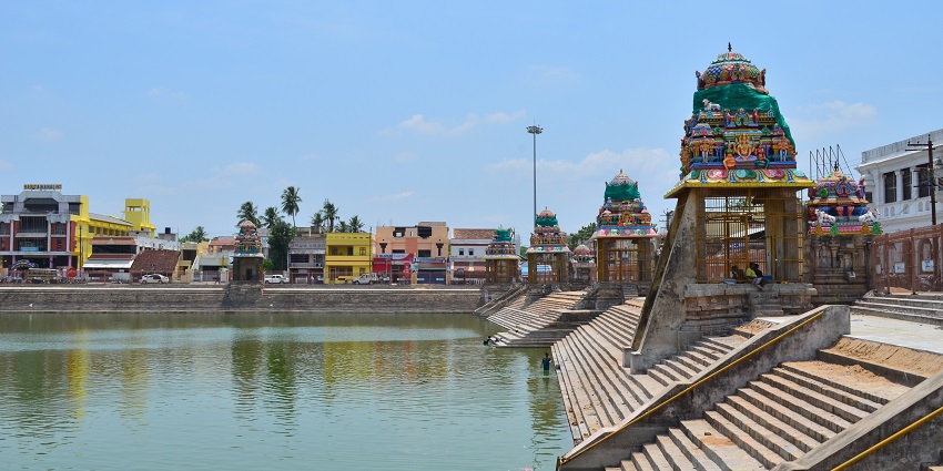 Wide view of Mahamaham Tank in Kumbakonam with people around the steps of the tank.