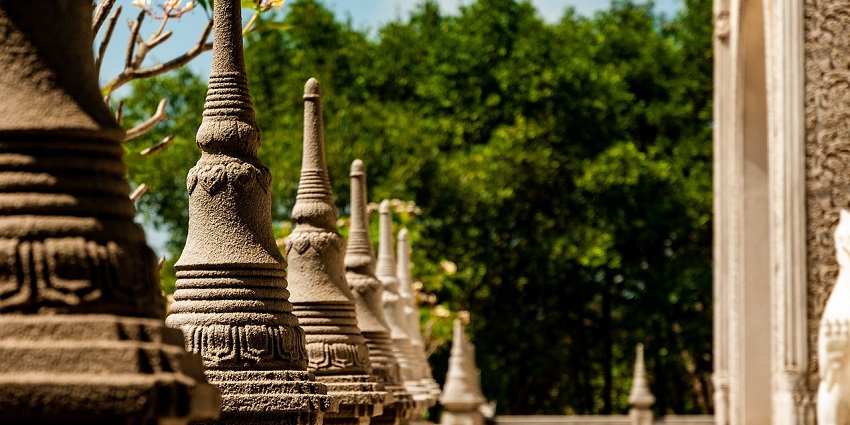 Beautiful pagoda with intricate design and golden accents, surrounded by lush greenery under a blue sky