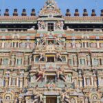 The outer view of a temple featuring Gopuram artwork consisting of various deities.