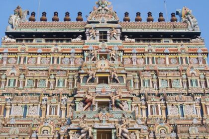 The outer view of a temple featuring Gopuram artwork consisting of various deities.