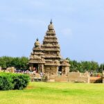 A distant side view of the ancient Mamallapuram Temple around which people are present.