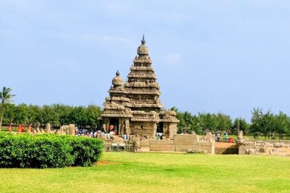 A distant side view of the ancient Mamallapuram Temple around which people are present.