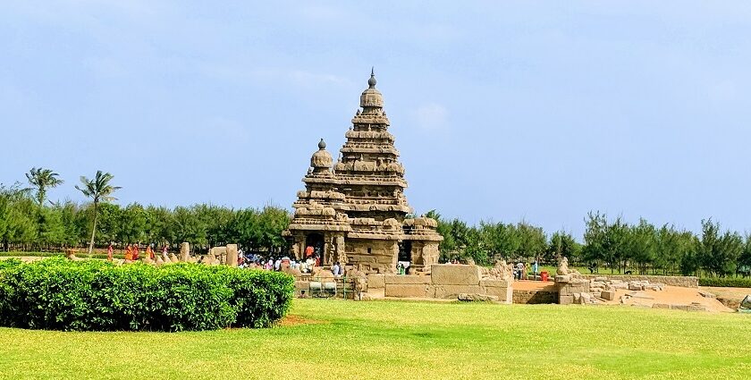 A distant side view of the ancient Mamallapuram Temple around which people are present.