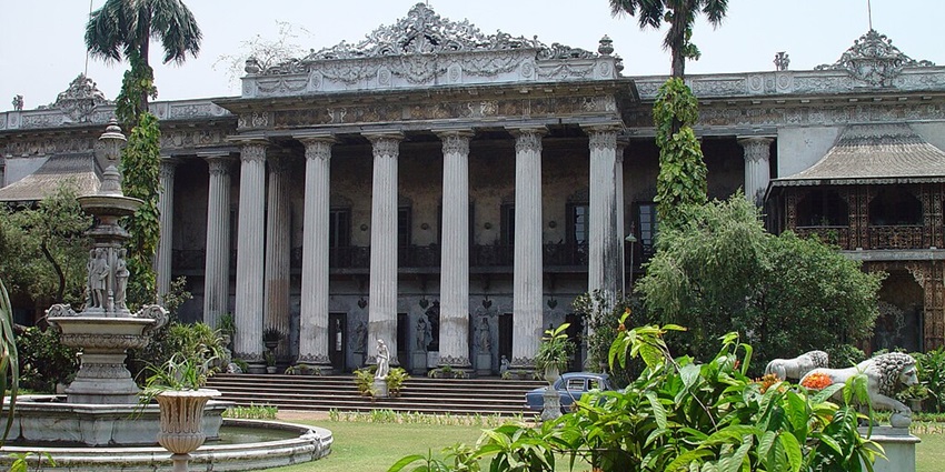 A picture of a beautiful palace located in Kolkata, with a lush garden in front of it