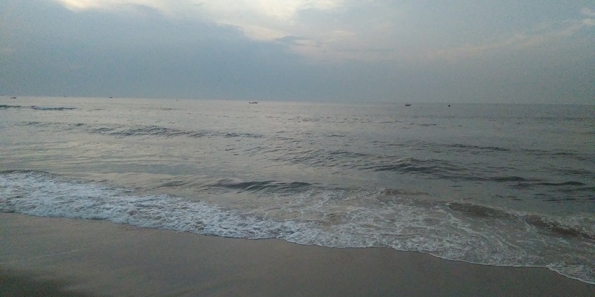 Cloudy skies over Marina Beach, with waves gently lapping the shore in Chennai, India.