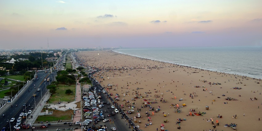A vibrant scene at Marina Beach, showcasing golden sands, gentle waves, and a clear blue sky.