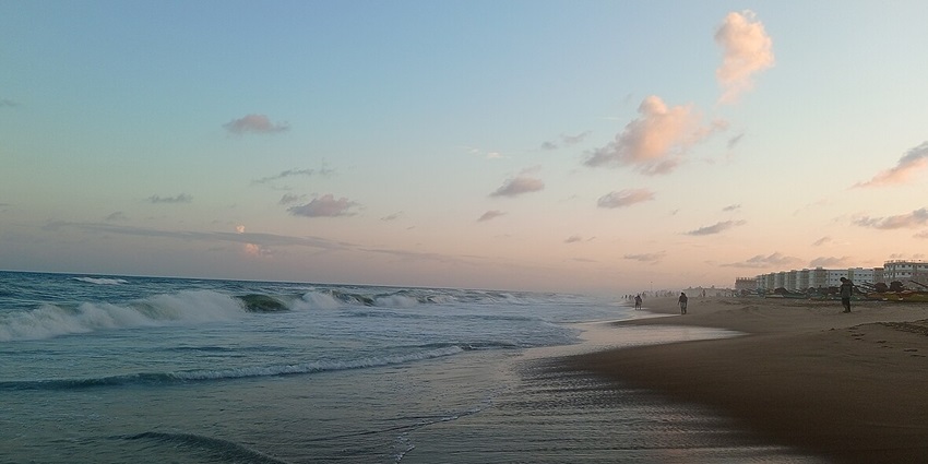 View of the waves on Marina Beach and sandy shores under the pink and blue sky.
