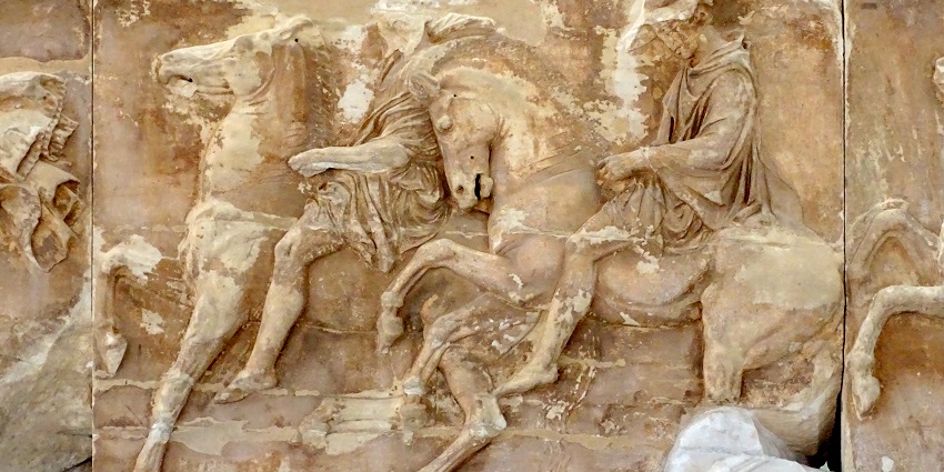 Sculpted stone at the Parthenon Gallery with detailed carvings of people riding horses.