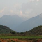 An image of a breathtaking view of the Meghamalai mountain range featuring greenery and misty peaks