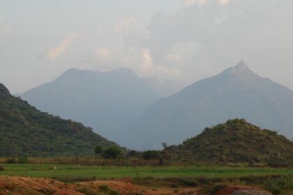 An image of a breathtaking view of the Meghamalai mountain range featuring greenery and misty peaks