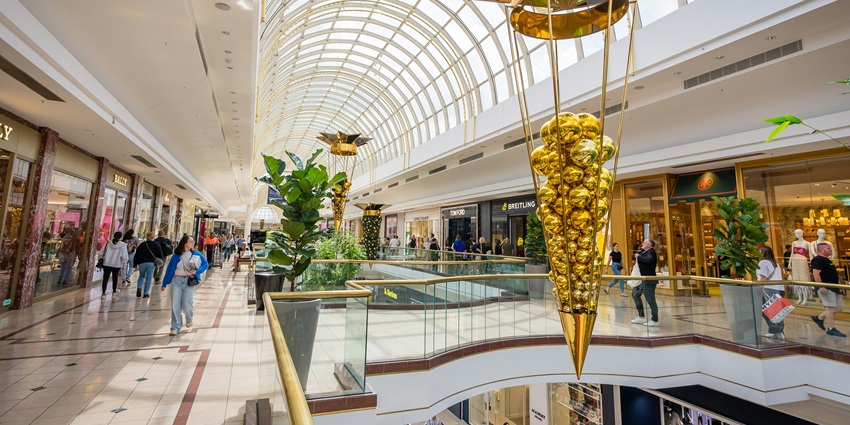 Interior of modern shopping mall decorated for holidays with shoppers walking around