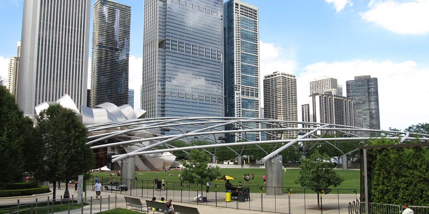 Millennium Park with people walking and sitting on the benches and tall buildings in view