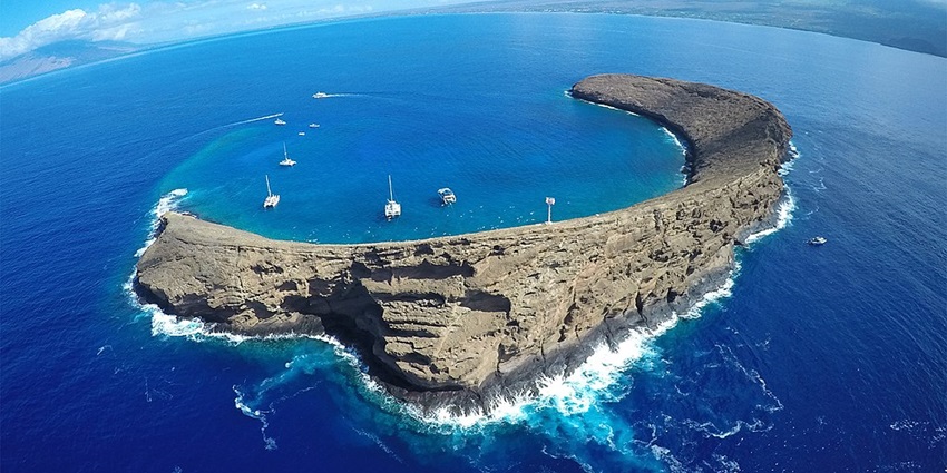 Molokini crater with the multiple boats around the crater and Hawaiian coastline