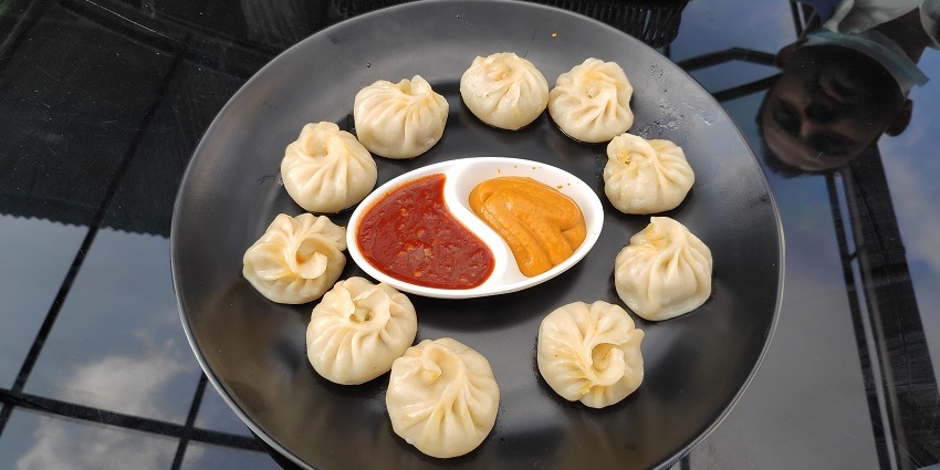 A plate of momos, served with spicy red chutney and mint chutney