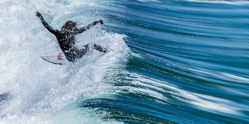 A surfer rides a wave in the ocean, a famous place to visit in Pondicherry for couples.