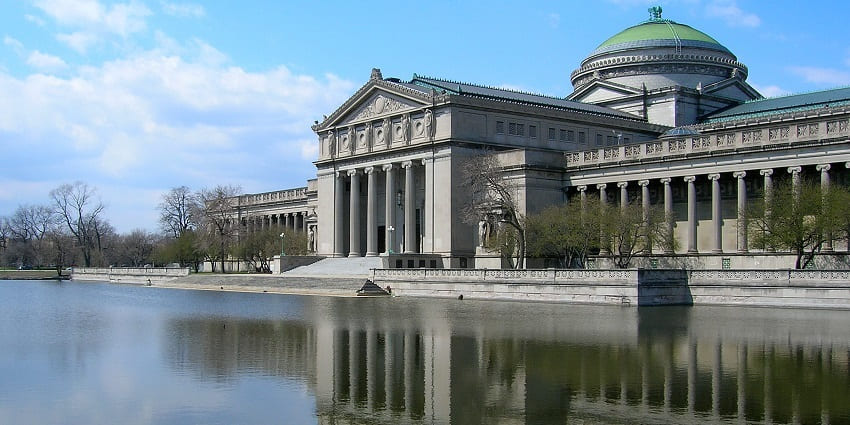 Side view of the Museum of Science and Industry of Chicago with a clear water lagoon