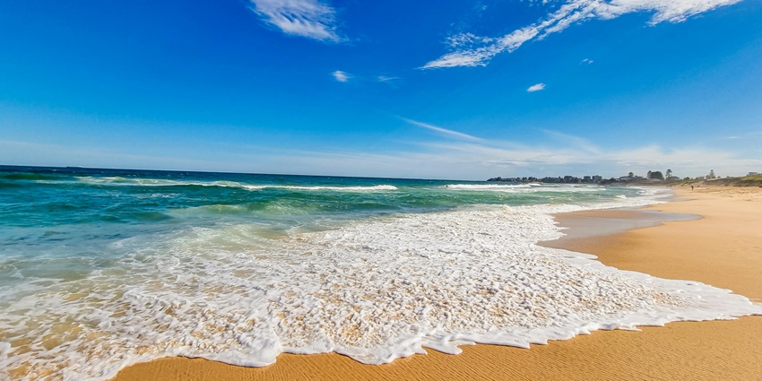 Nagercoil Beach is a beautiful beach under a clear blue sky, featuring soft sands and gentle waves lapping at the shore.