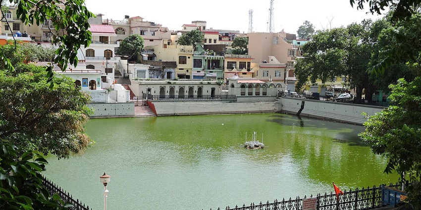 A serene view of the waters of Rani Tal surrounded by quaint houses & greenery.