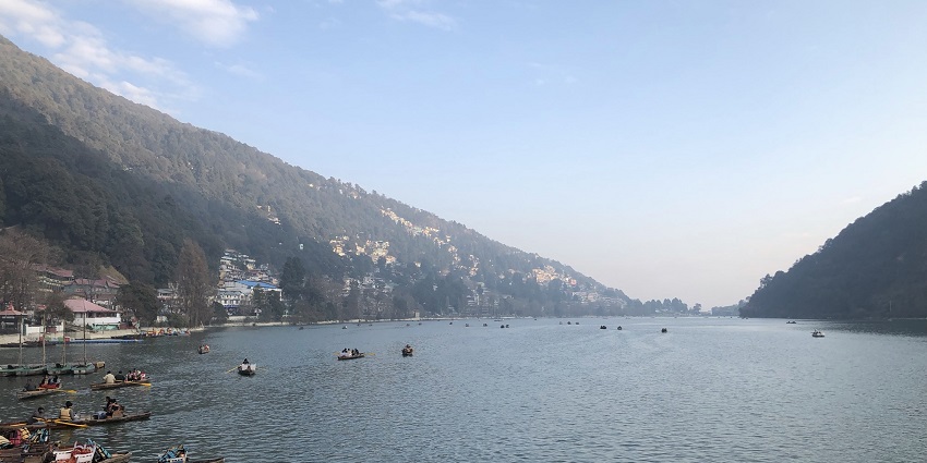 Popular boating activity at Nainital Lake with surrounding high peaked mountains.