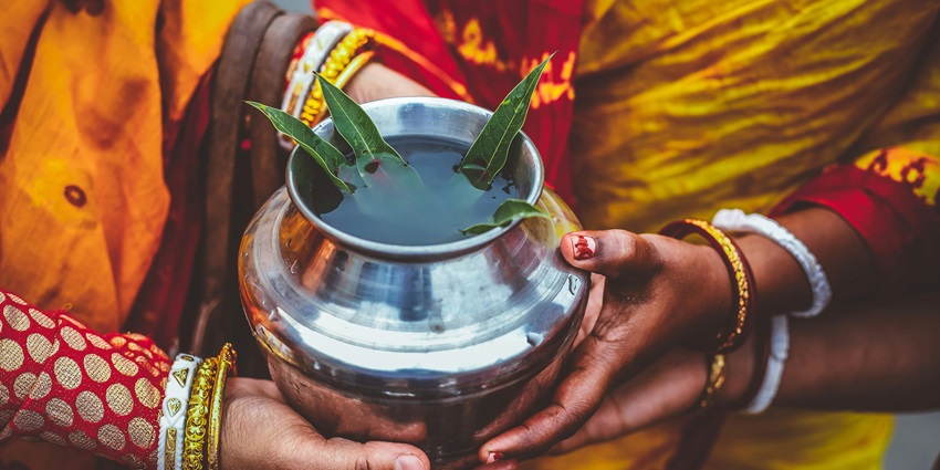 People holding a silver metal pot, part of a traditional ceremony or ritual gathering